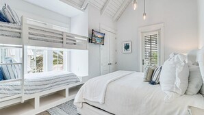 Quarto com beliche, cama grande e janela com persianas.