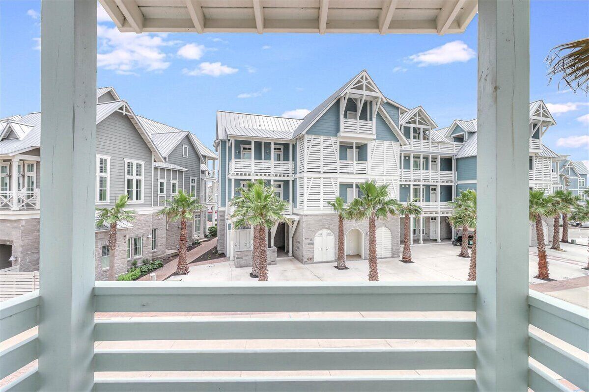 A beachfront property with multiple-story houses, a covered walkway, and palm trees.