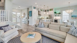 A spacious living area with a sofa, coffee table, and a staircase leading to an upper floor.