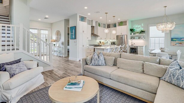 A spacious living area with a sofa, coffee table, and a staircase leading to an upper floor. - Ships and Giggles 276 HI (Port Aransas)