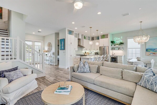 A spacious living area with a sofa, coffee table, and a staircase leading to an upper floor. - Ships and Giggles 276 HI (Port Aransas)