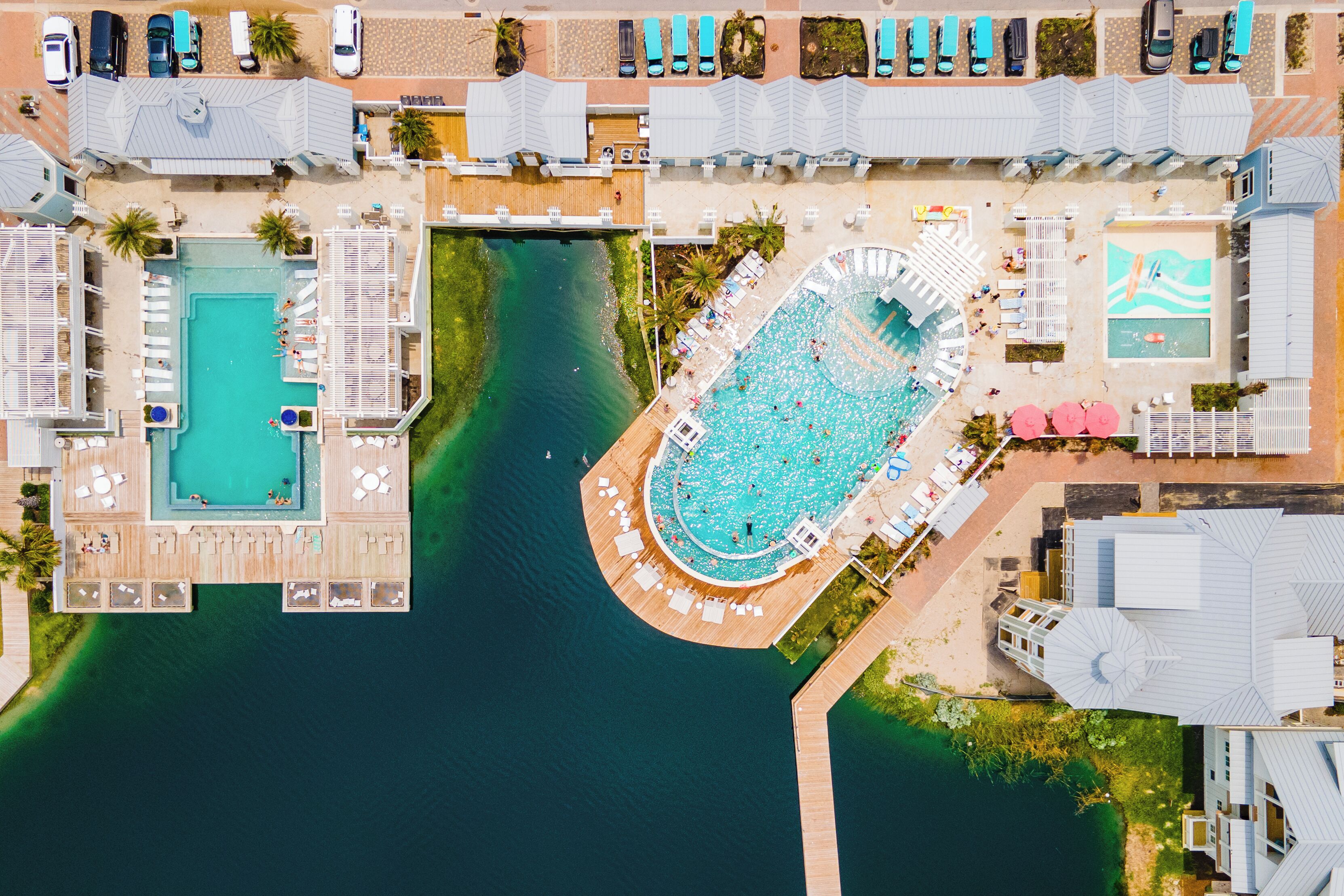 Eine Vogelperspektive eines Resorts mit mehreren Schwimmbecken, einer Marina und verschiedenen Annehmlichkeiten am Strand.