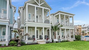 A multi-story residential building with a porch, multiple balconies, and a well-maintained lawn. - Sandpiper Cottage 239 HL (Port Aransas)