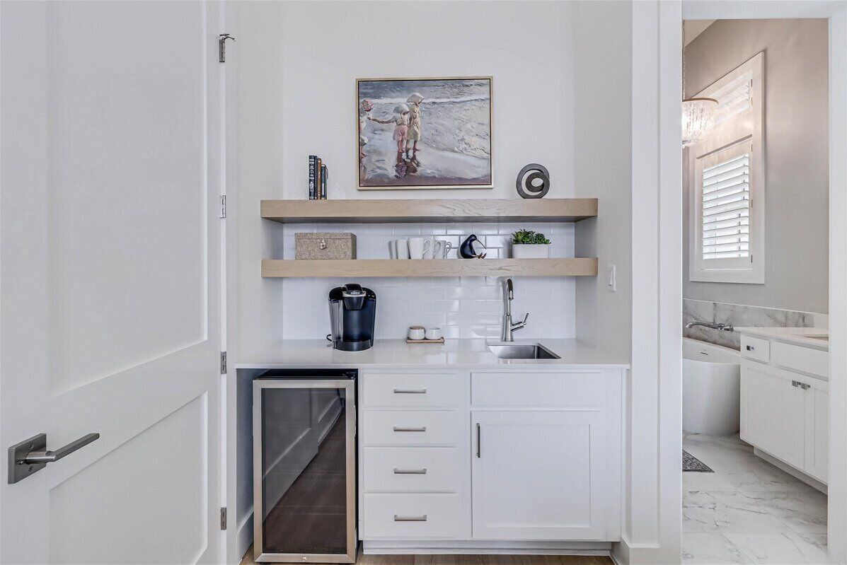 A compact kitchen with white cabinetry, a built-in oven, and a coffee maker.