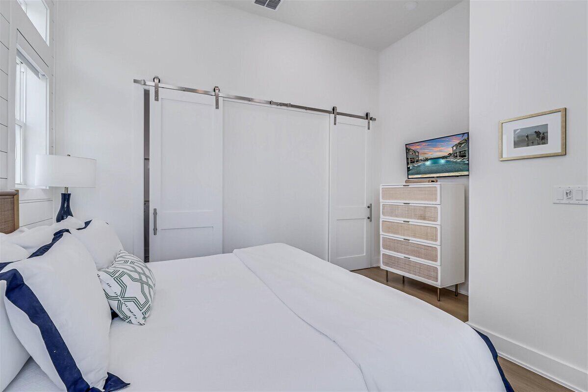 Un dormitorio con cama, armario, cómoda y un cuadro en la pared.