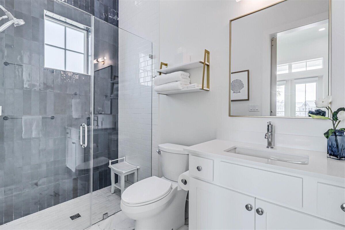 A modern bathroom with a glass shower enclosure, a white toilet, a vanity with a sink, and a large mirror.