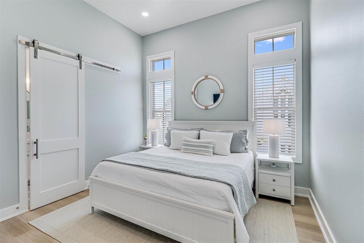 A bedroom with a bed, bedside tables, a mirror, and a window with blinds.