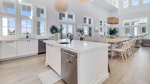 A spacious kitchen with a central island, large windows, and modern pendant lights. - Lakeside Luxury 230 LAK (Port Aransas)