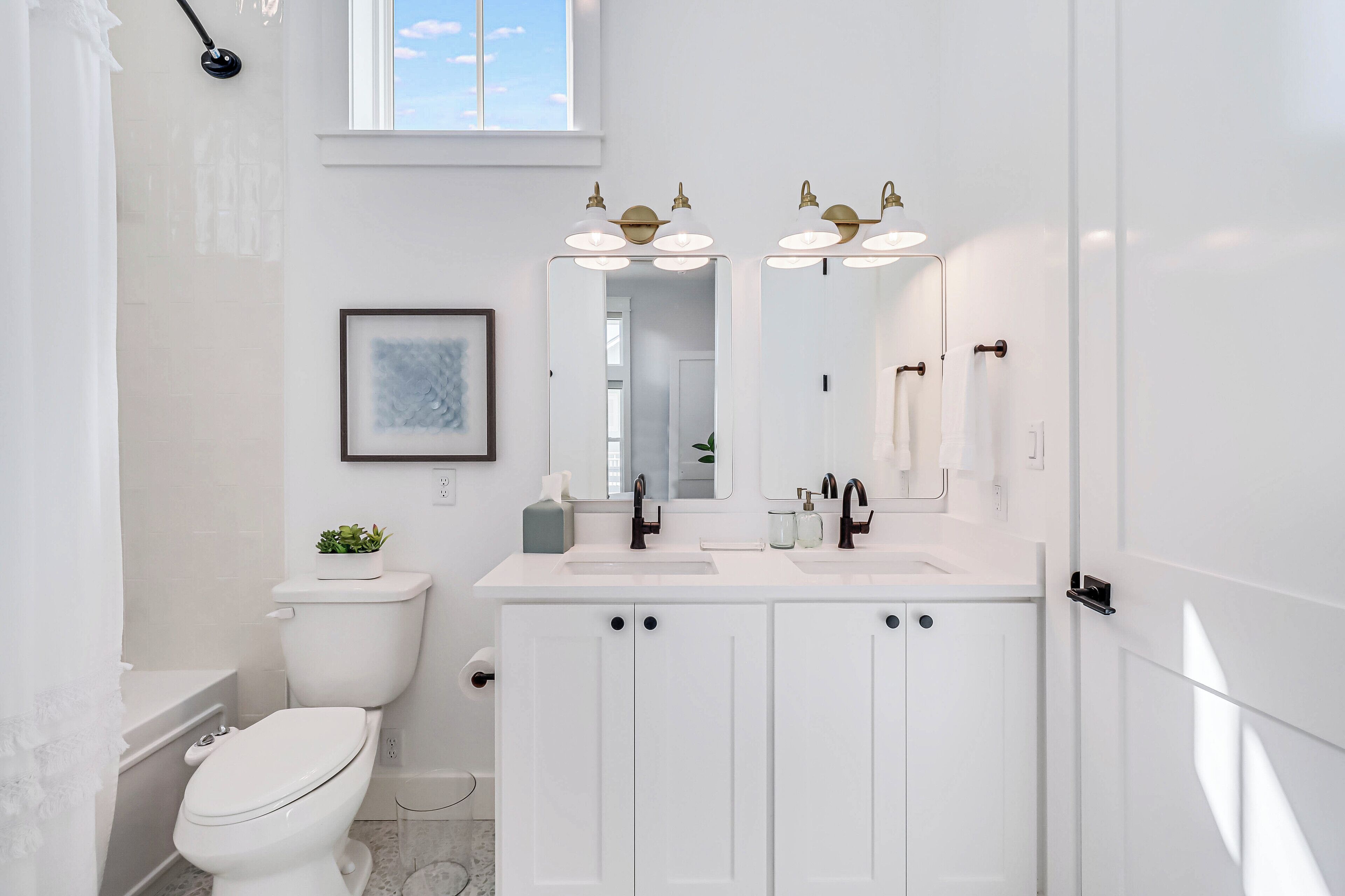 A modern bathroom with a white toilet, a double sink vanity, and a large mirror.