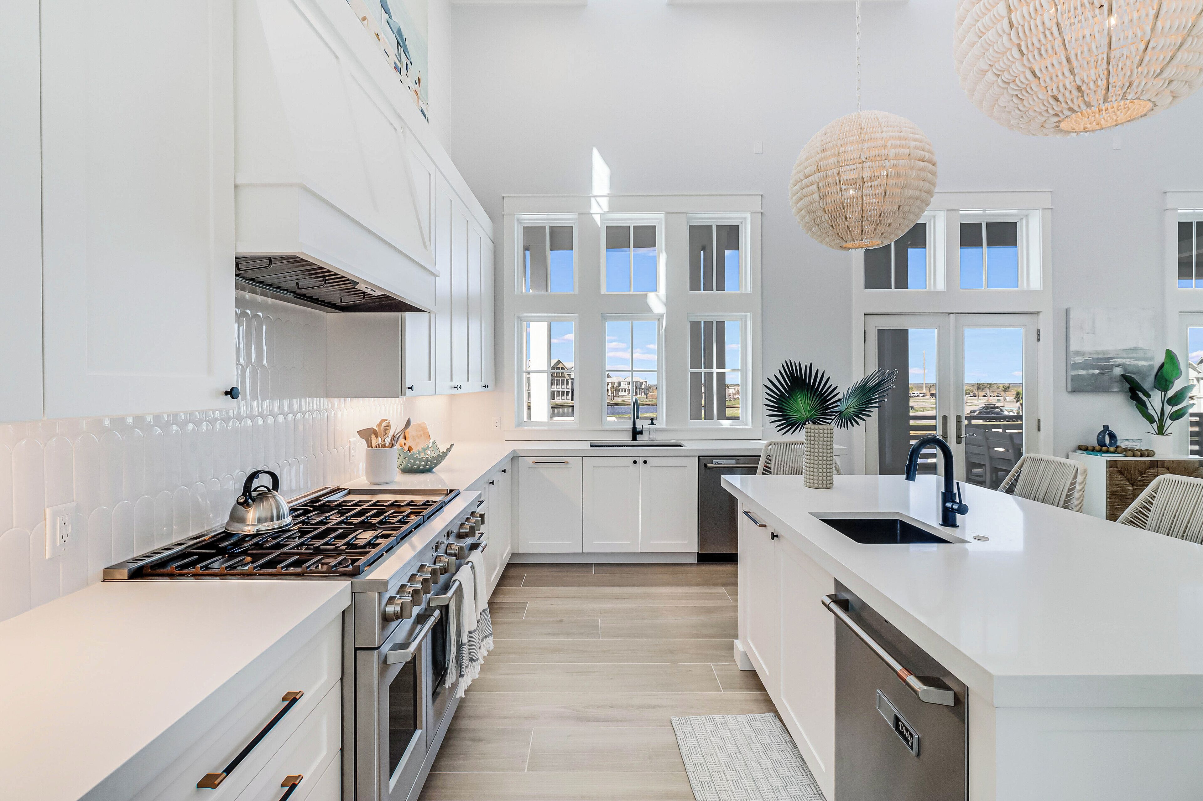 A modern kitchen with white cabinetry, a large island with a sink, and a view of the city through large windows.