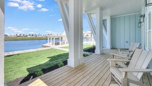 A covered outdoor area with wooden deck, white columns, and Adirondack chairs. - Lakeside Luxury 230 LAK (Port Aransas)