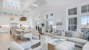 A spacious living area with a large sofa, a dining table, and a kitchen in the background. - Lakeside Luxury 230 LAK (Port Aransas)