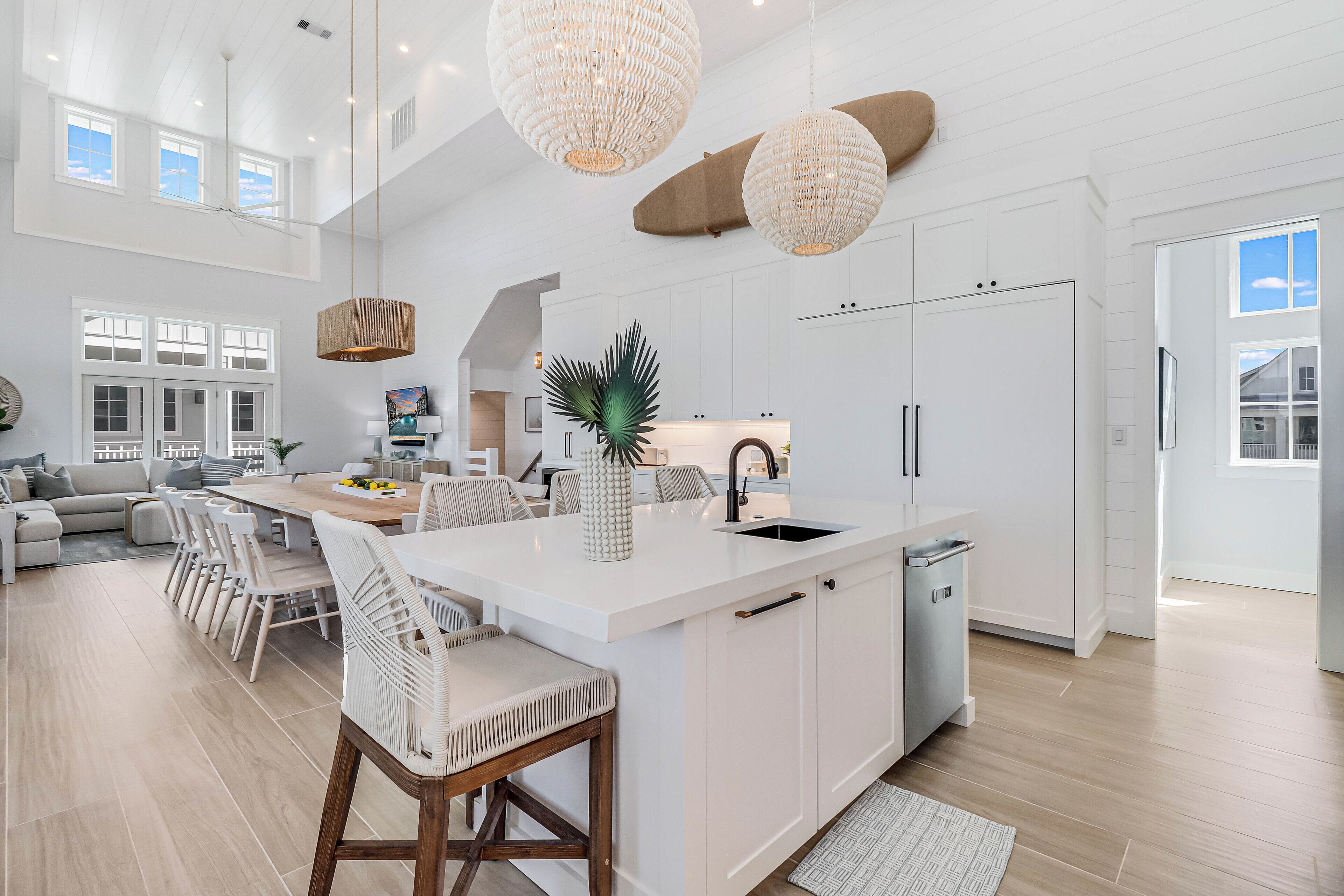 A spacious kitchen with a large island, white cabinetry, and pendant lighting.