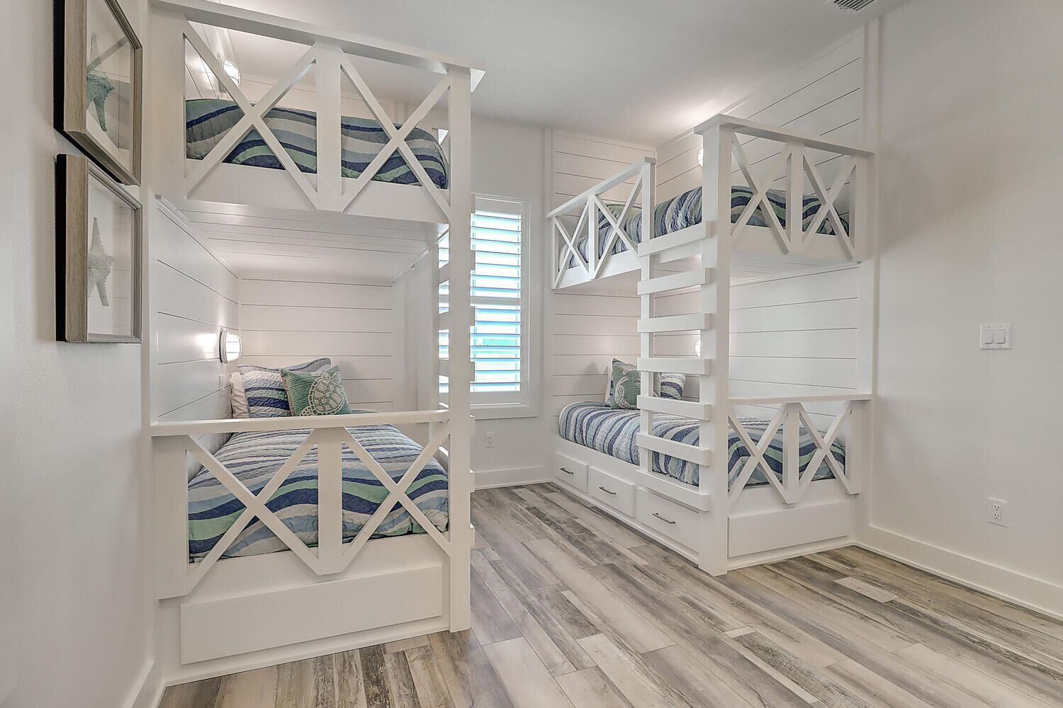 Una habitación con literas, piso de madera y ventana con persianas.