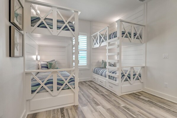 A room with bunk beds, wooden flooring, and a window with blinds. - The Great White 306 DAR (Port Aransas)