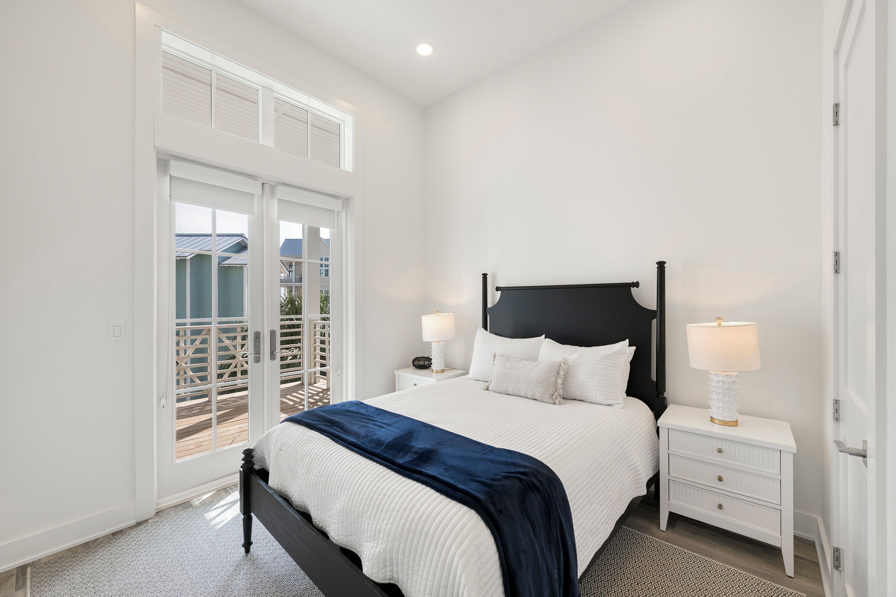 Une chambre à coucher comprenant un lit, deux tables de chevet, une commode, une fenêtre avec vue et une porte.