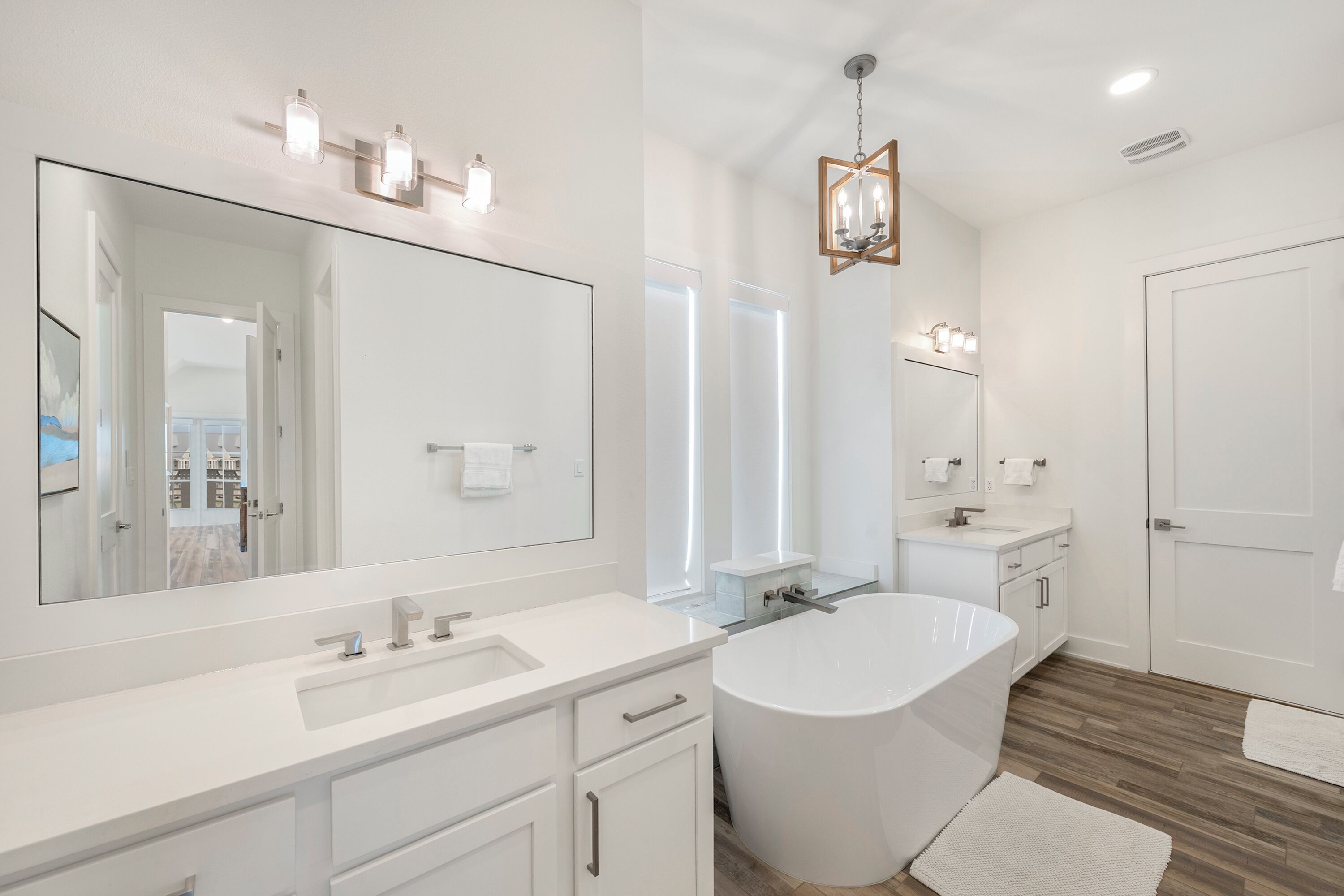 Un bagno moderno con uno specchio grande, una vasca da bagno freestanding e un mobile lavabo.