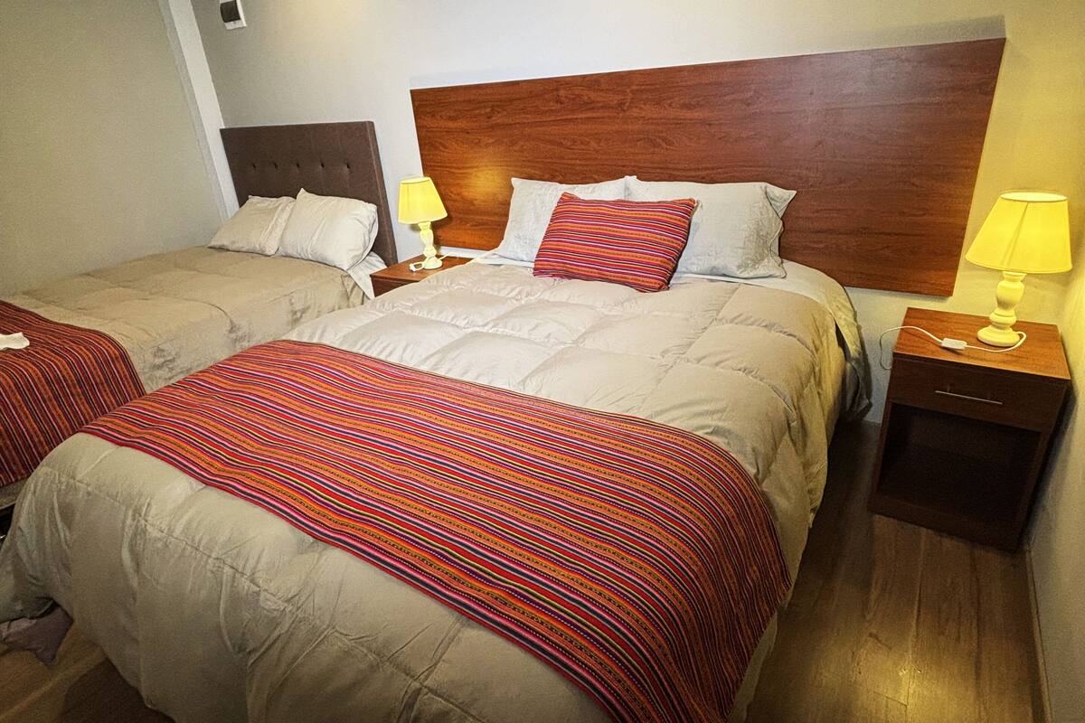 Una habitación de hotel con dos camas, cabeceros de madera y lámparas de noche.