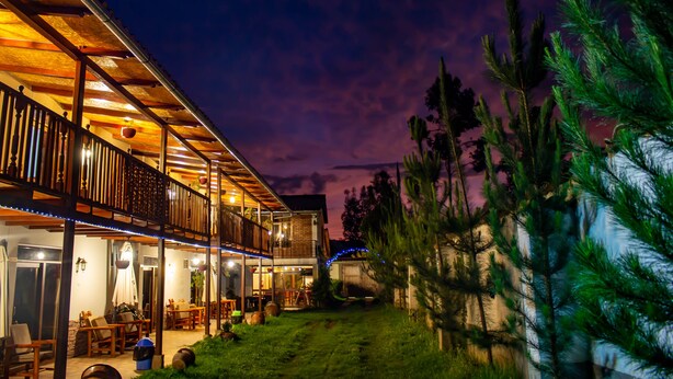 A two-story building with a balcony, outdoor seating, and a well-lit entrance.