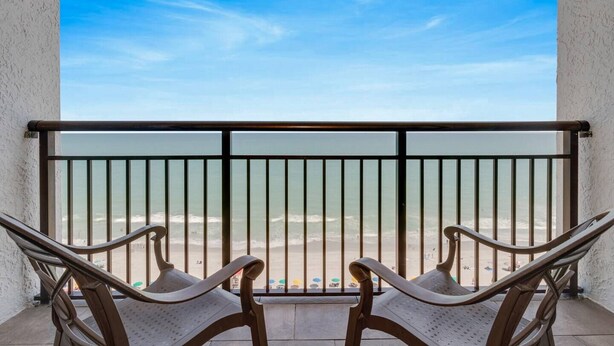 Ein Balkon mit zwei Stühlen und Blick auf den Strand.