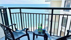 A balcony with two chairs and a table, overlooking a body of water.