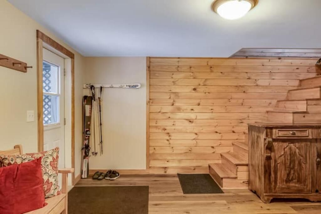 Een houten interieur met een trap, een deur, een kapstok en een kast.