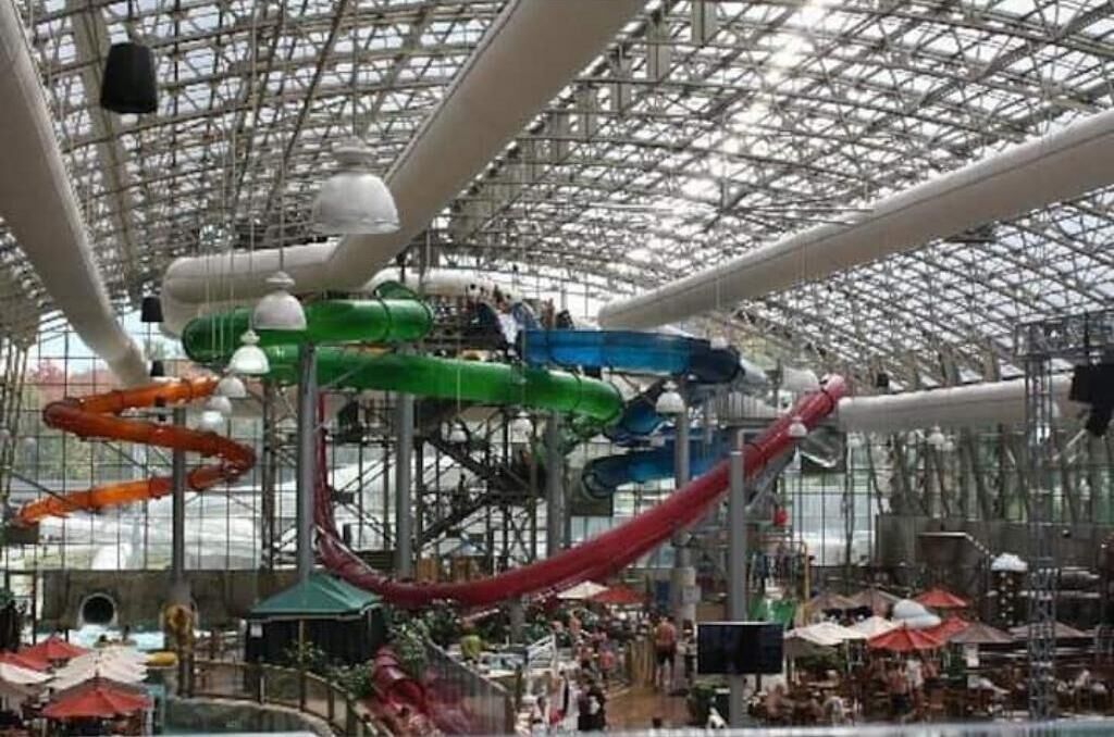 An indoor water park with multiple slides and a high glass ceiling.