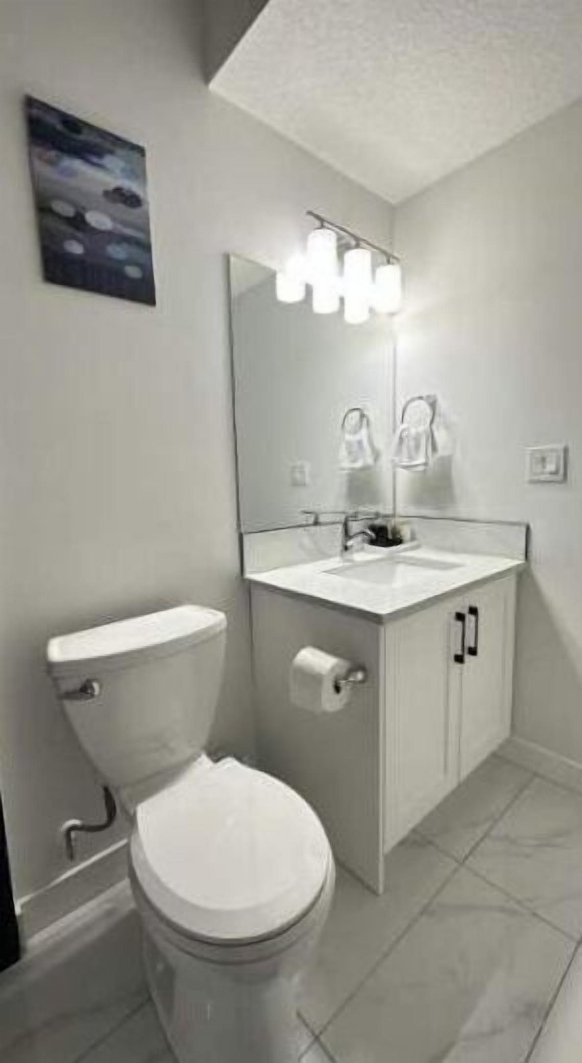 Un bagno moderno con il water, un lavandino e uno specchio.