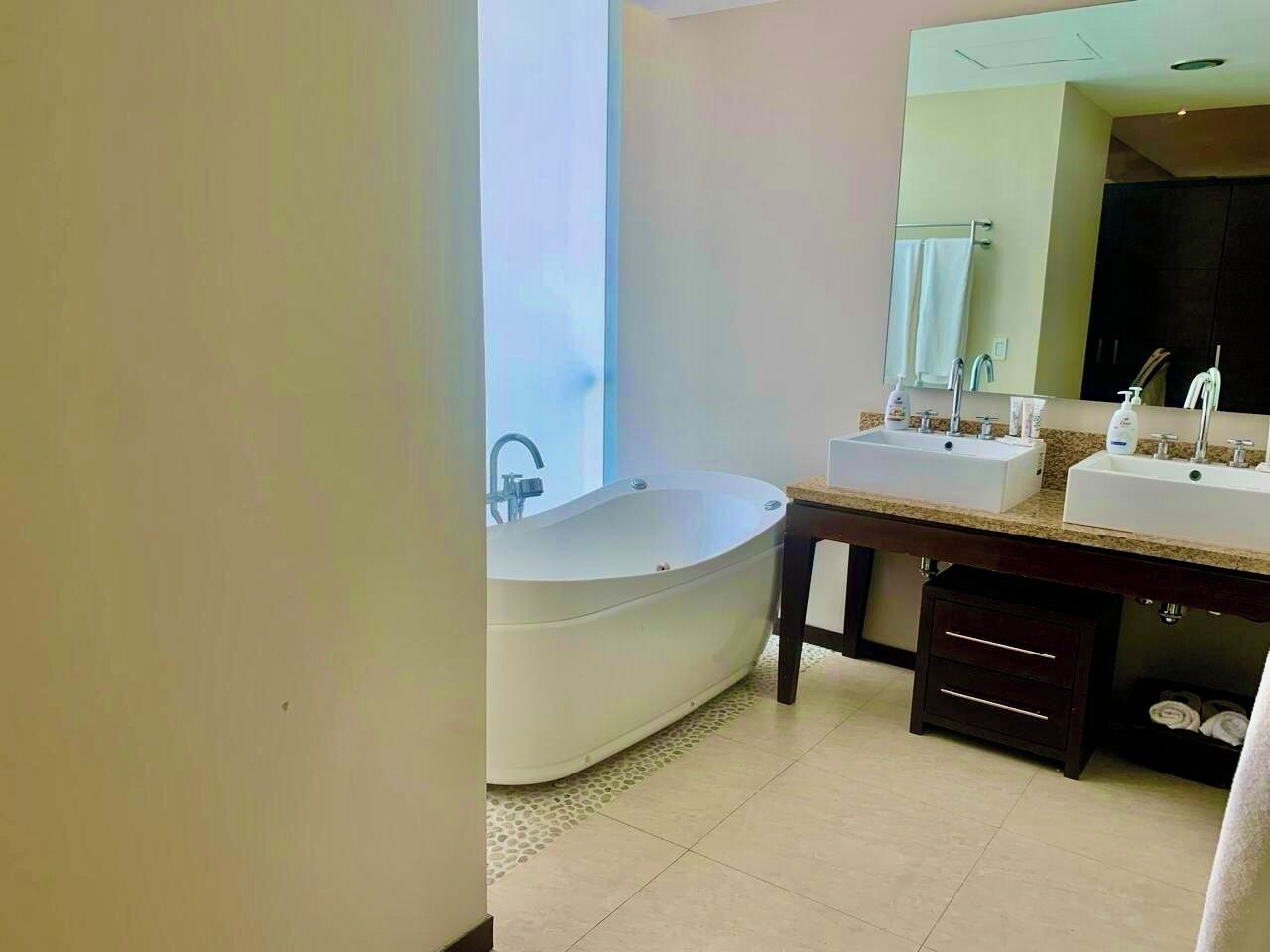 Une salle de bain moderne avec une baignoire sur pieds, deux vasques et un grand miroir.