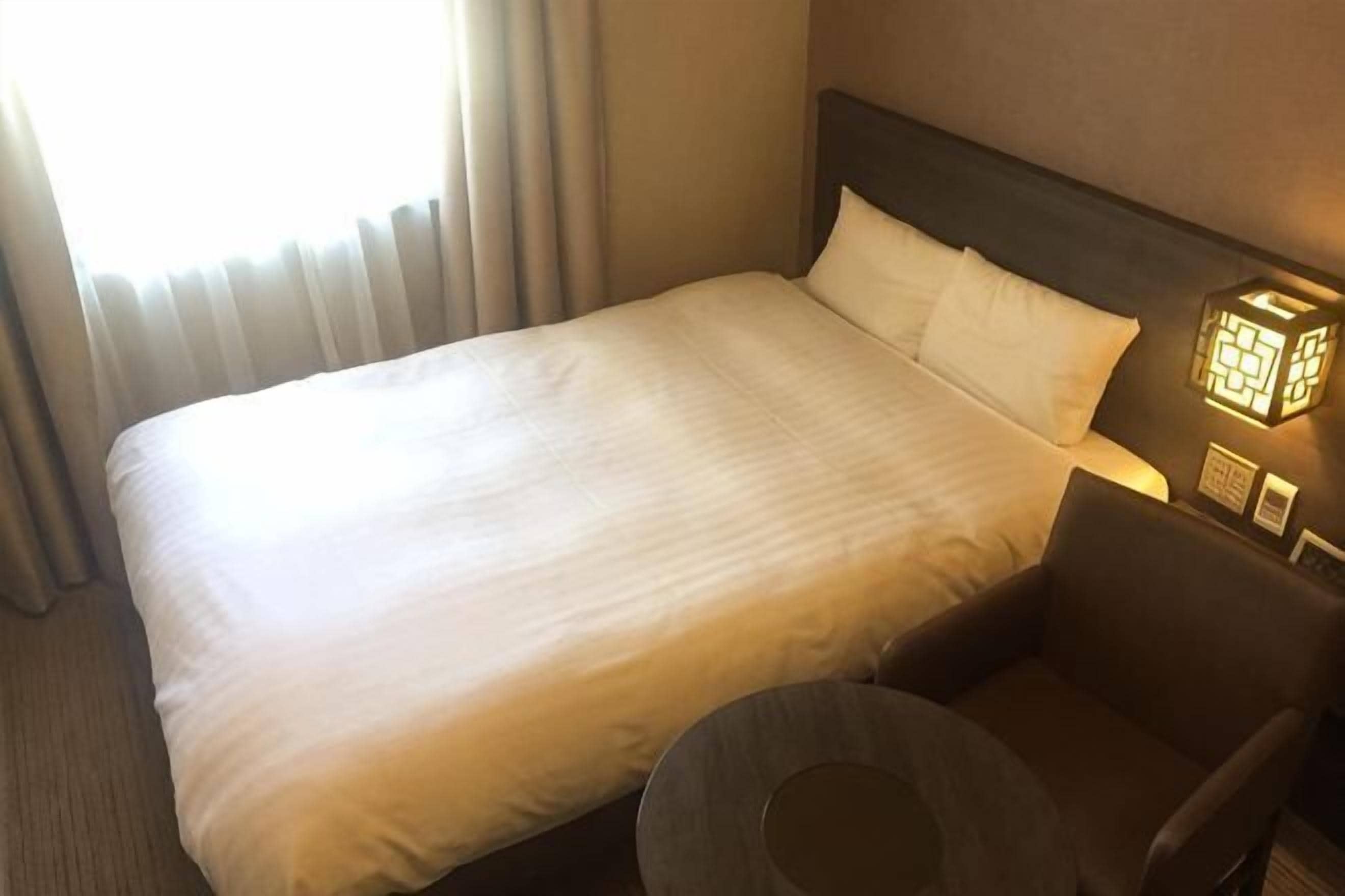 Ein Hotelzimmer mit einem Bett, einem runden Tisch und einer Wandleuchte.