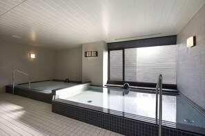 A spa area with two hot tubs, a tiled floor, and a window with blinds. - Hotel Dormy Inn Nagasaki Shinchichukagai (Nagasaki City)