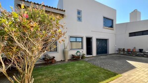 Una casa moderna de dos pisos con entrada pavimentada y césped bien cuidado.