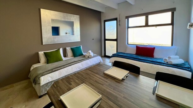 Una habitación de hotel moderna con una cama grande, una mesa de comedor y una ventana con vistas.