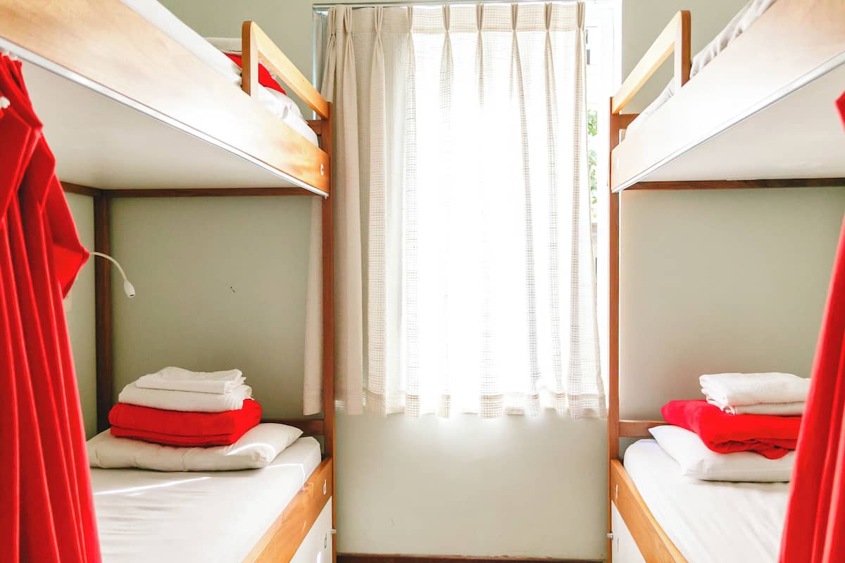 A dormitory room with bunk beds, a curtain, and neatly folded towels.