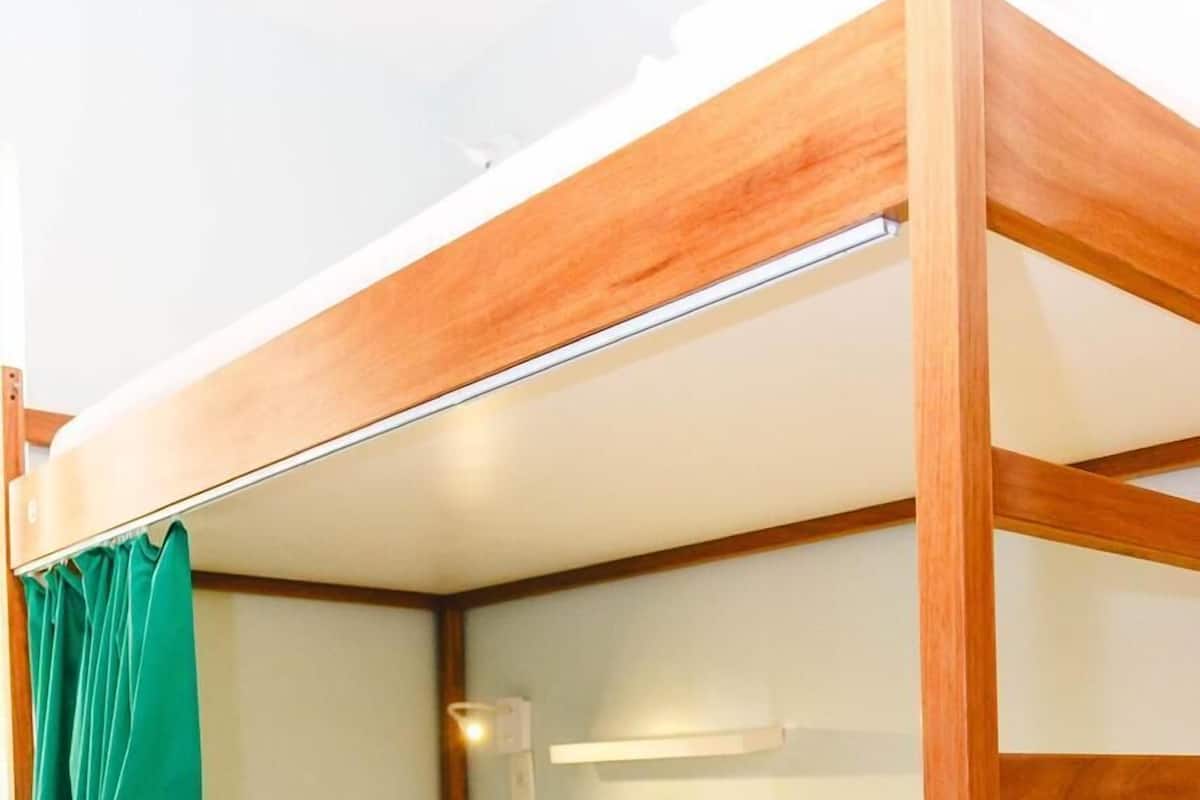 A bunk bed with a wooden frame and white bedding.