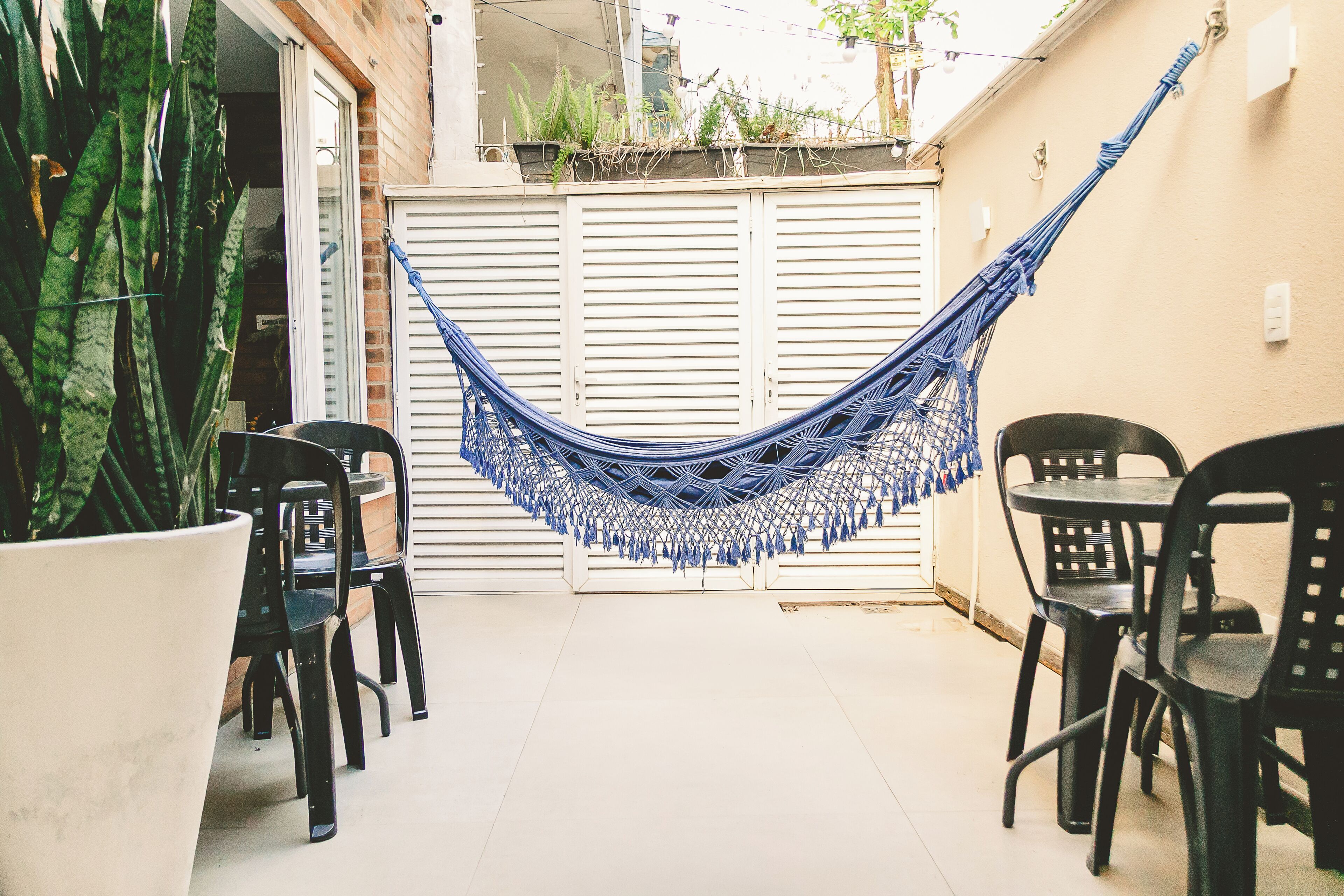 A hammock, chairs, and a potted plant in a patio area.