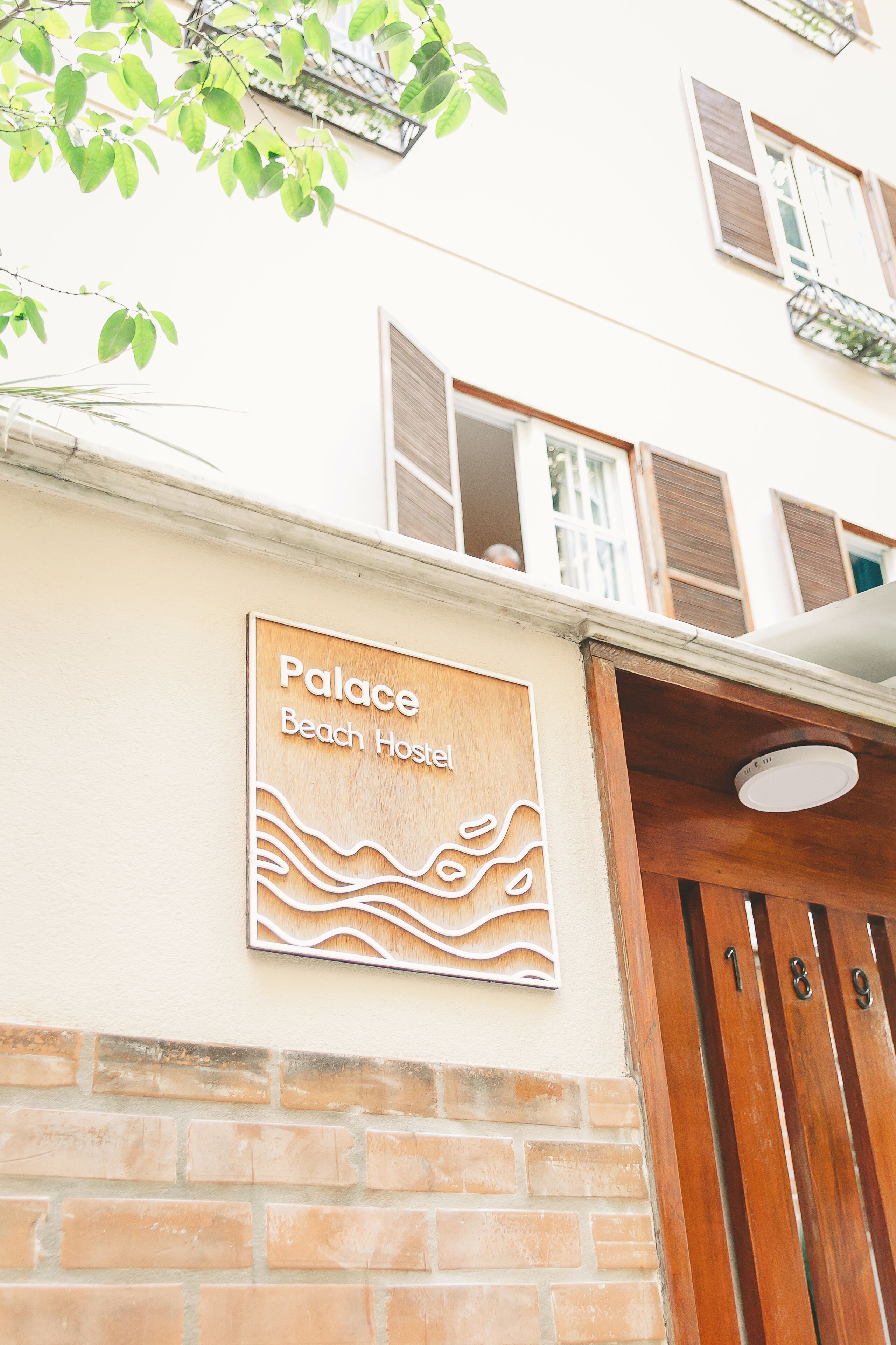 A building with a sign that reads 'Palace Beach Hostel' and a wooden door with the number '18'.