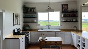 A kitchen with white cabinets, a wooden countertop, a window with a view of the outdoors, and a hanging light fixture. - Farmhouse in beautiful Ferndale. Big enough for the whole family! (Ferndale)