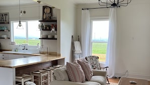 A spacious living area with a kitchen, a large window with a view, and a chandelier. - Farmhouse in beautiful Ferndale. Big enough for the whole family! (Ferndale)