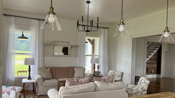 A spacious living room with a wooden dining table, a sofa set, and a large window with curtains. - Farmhouse in beautiful Ferndale. Big enough for the whole family! (Ferndale)