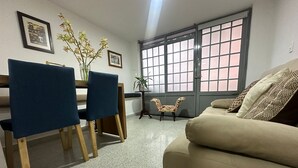 Un soggiorno con un divano color beige, un tavolo da pranzo con sedie, una poltrona a fantasia e un'ampia finestra con vista.