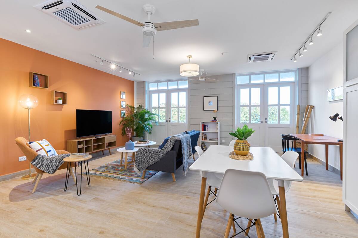 A modern living room with a sofa, a dining table, and a TV.