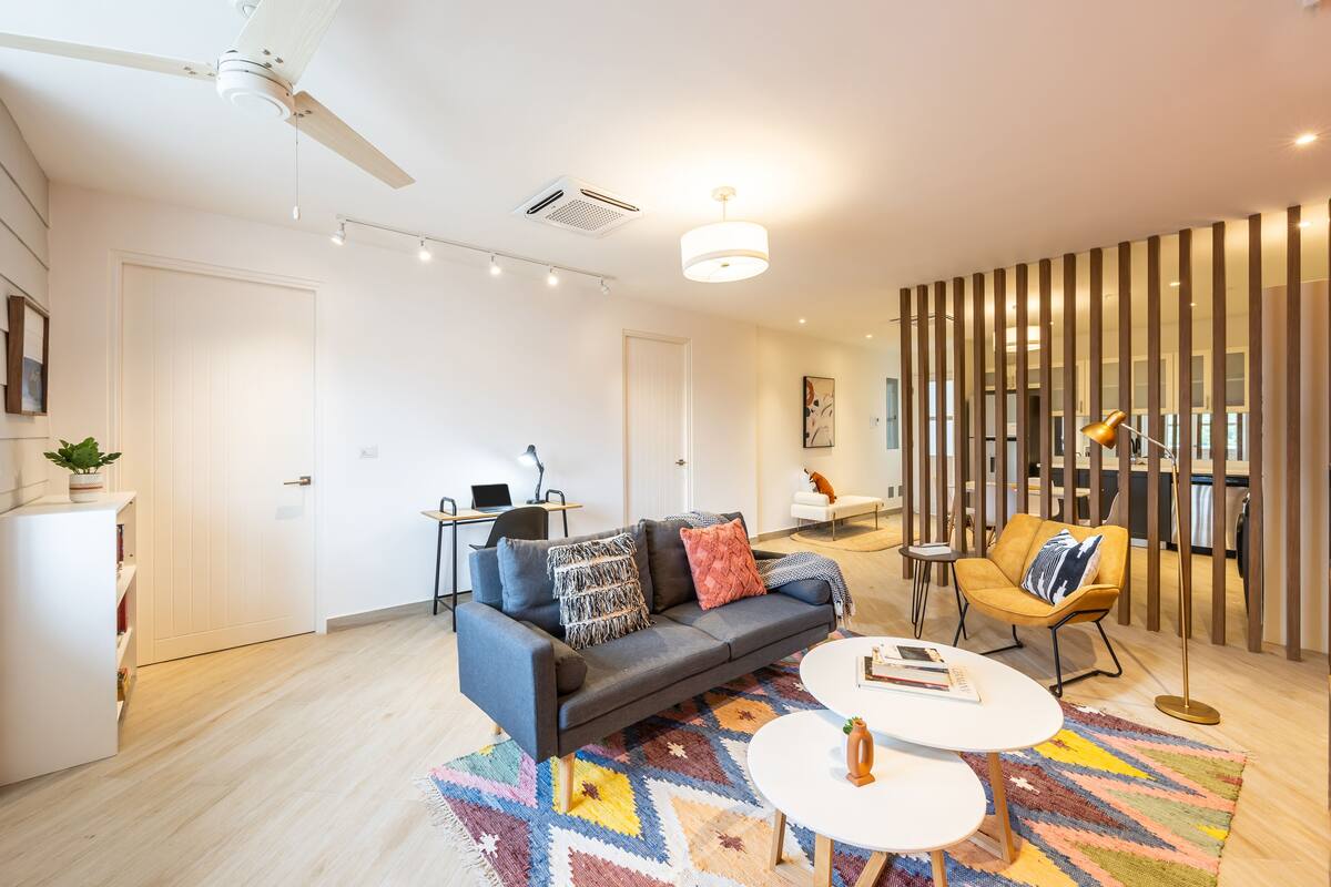 A modern living room with a sofa, coffee table, and a patterned rug.