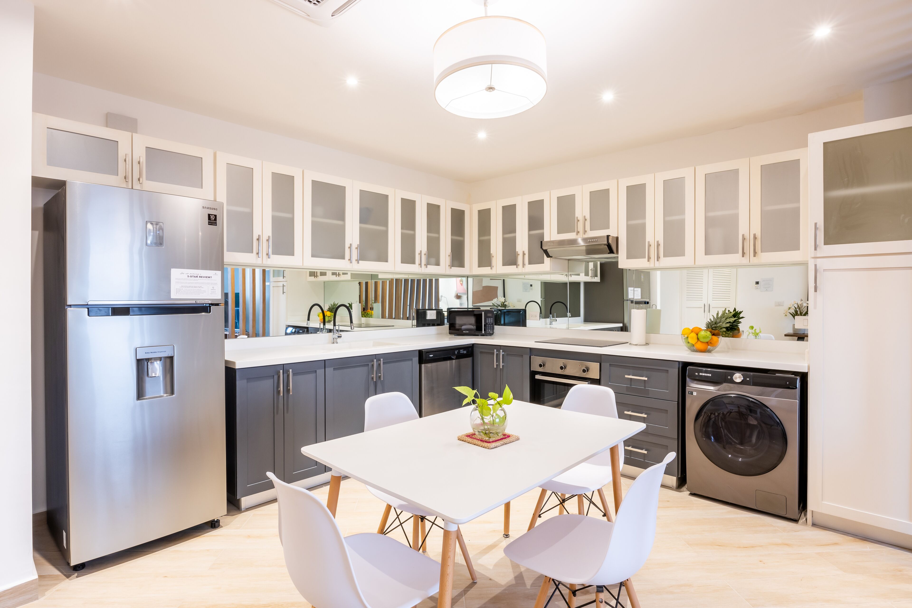 A modern kitchen with white cabinets, stainless steel appliances, and a dining area with a table and chairs.
