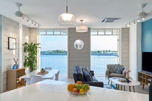 A modern living room with a dining area, a sofa, a TV, and a view of the water. - Casa La Costa By Wynwood House (Panama City)