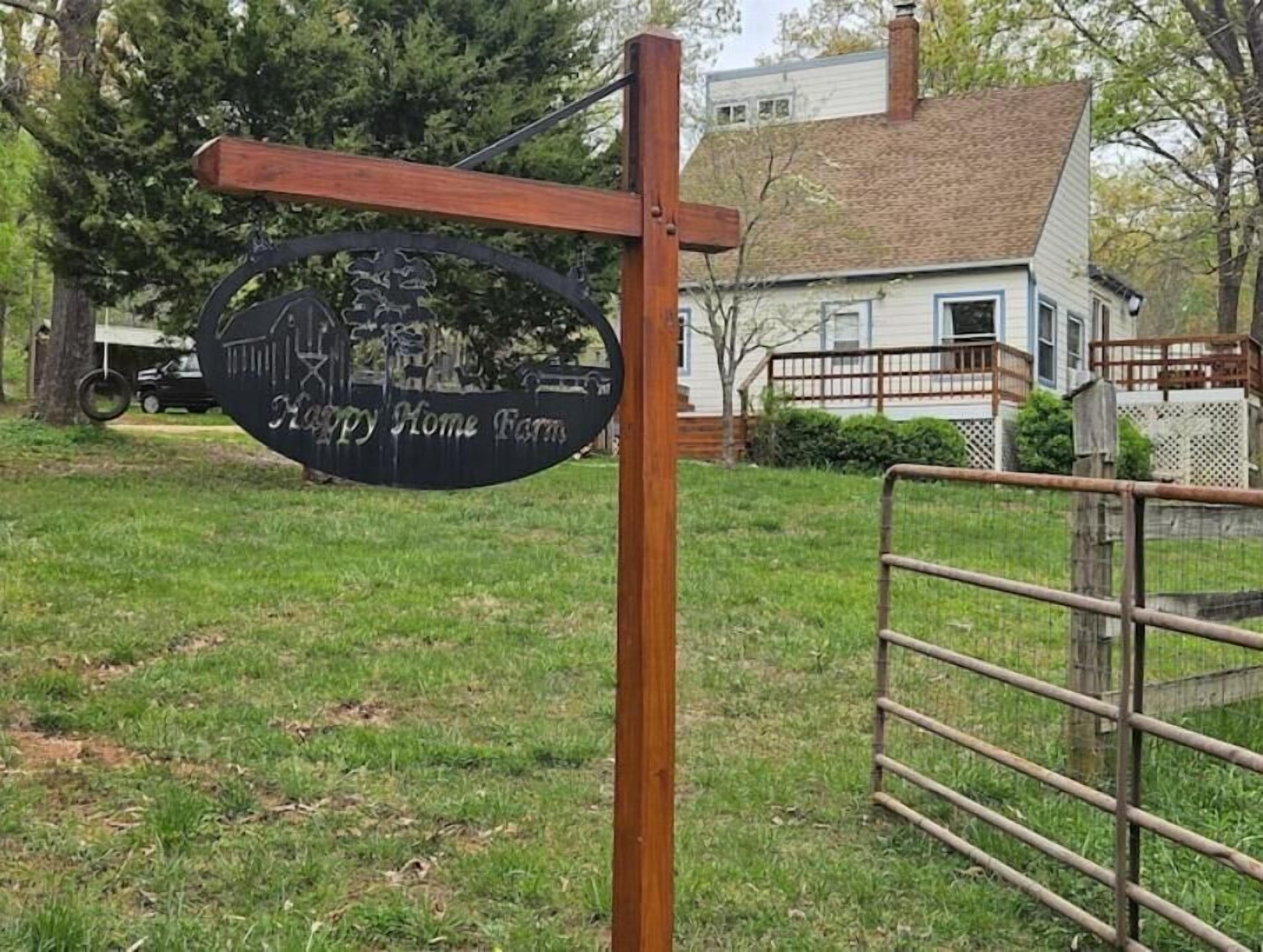 A wooden sign with a metal gate in front of a house.