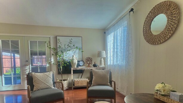 A living room with two sofas, a coffee table, and a round mirror. There is a potted plant and a vase on a side table.