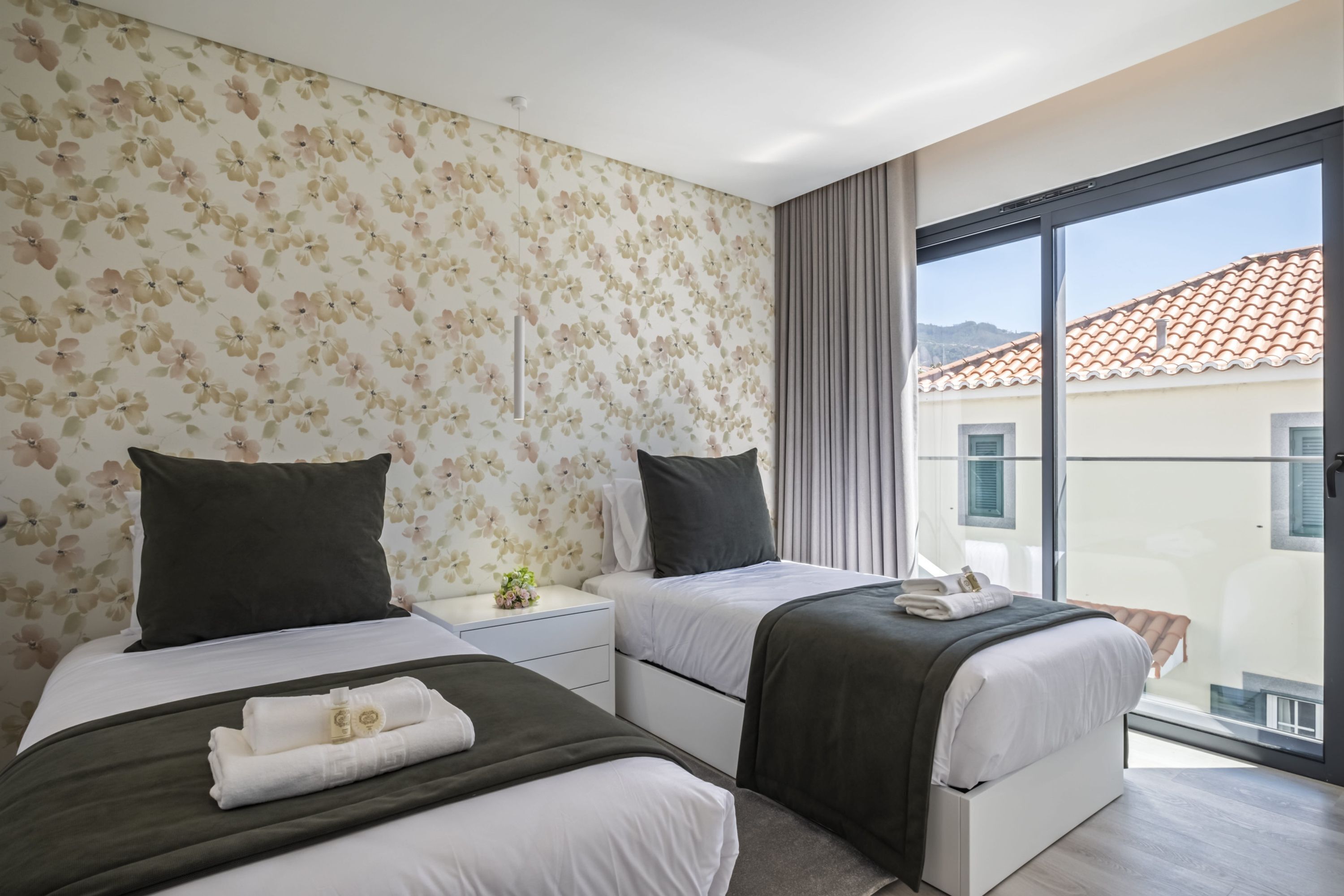 Une chambre d’hôtel avec deux lits, une grande fenêtre et un balcon.