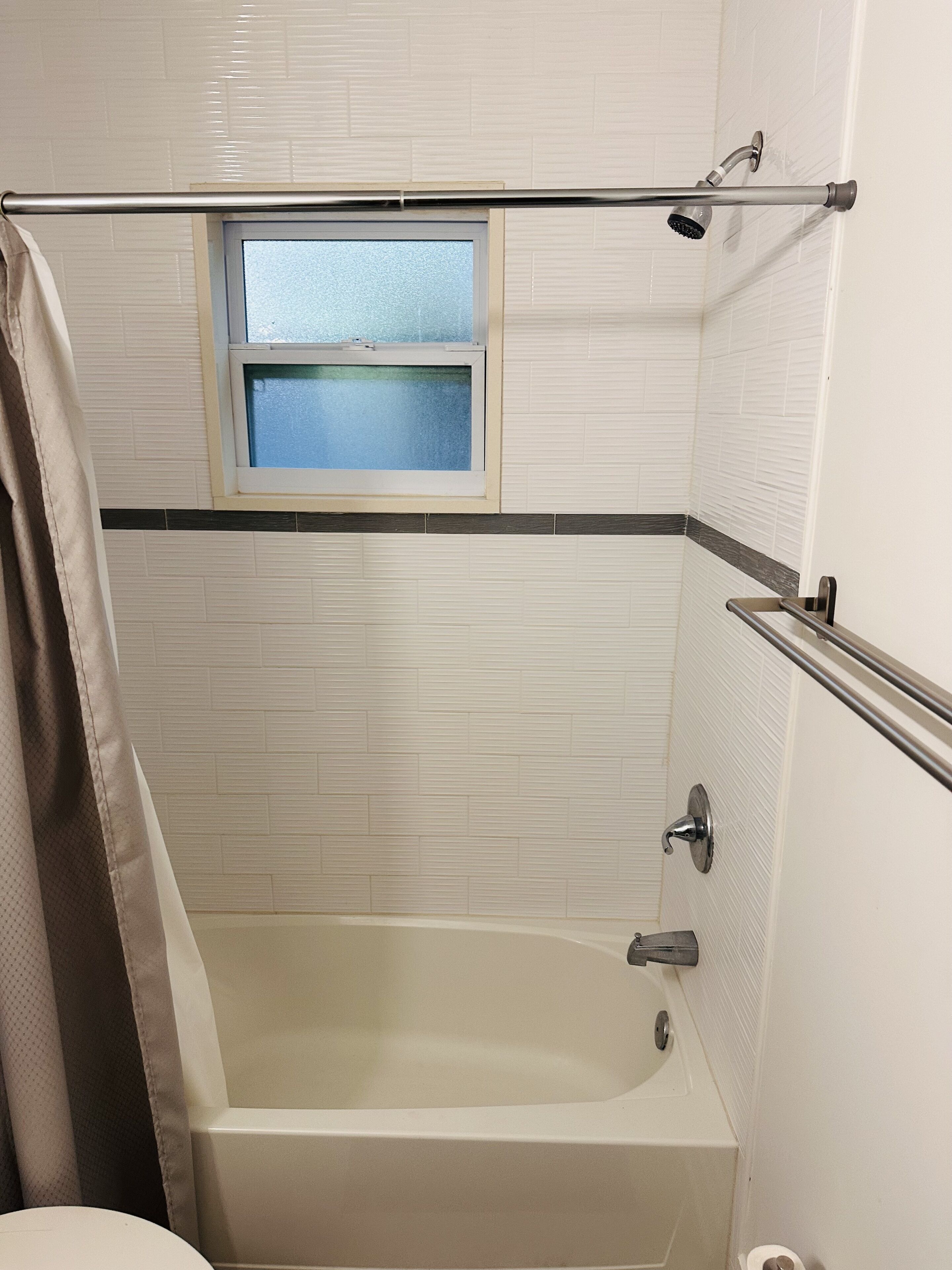 Ein Badezimmer mit einer Badewanne, einem Fenster und einer Duschbrause.