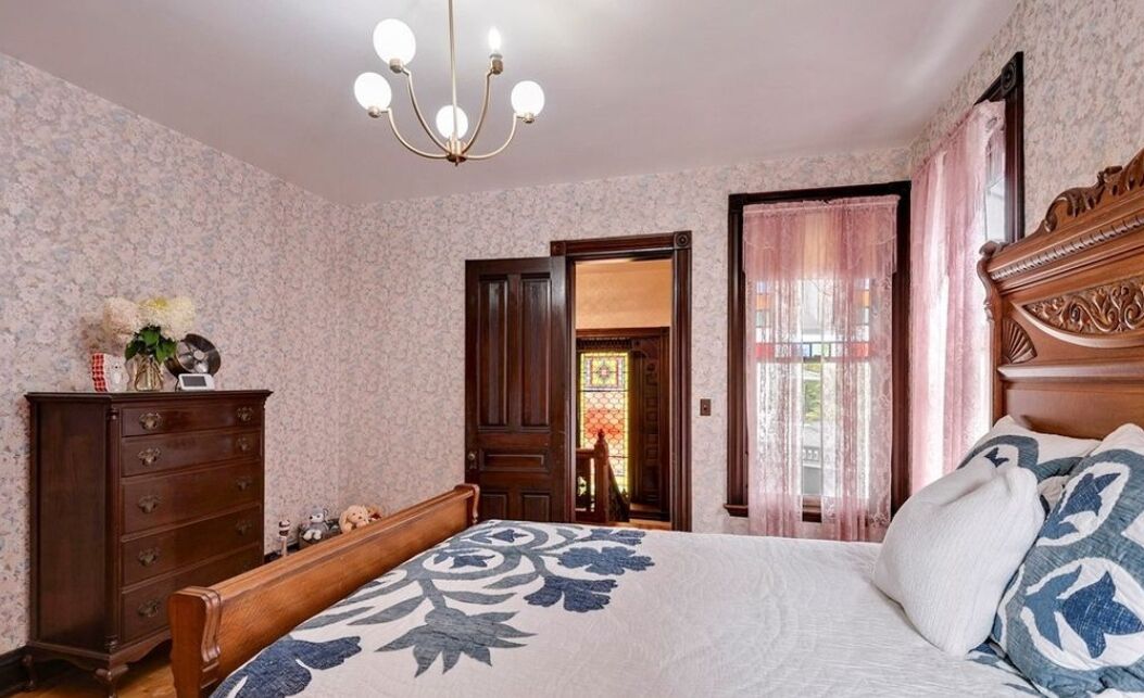 Un dormitorio con una cama grande, cómoda de madera y una araña.
